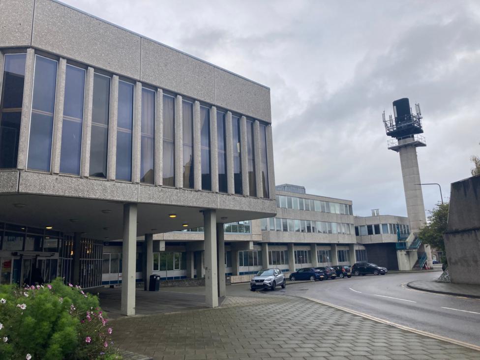 Brunton Theatre, a grey brutalist building on stilts with thin windows and cars parked under it.