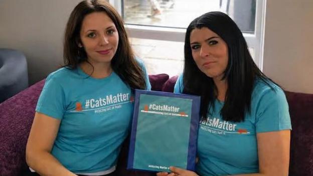 Tiya Ivy (left) and Mandy Hobbis (right) both wear T-shirts with '#CatsMatter' printed across it. Between them, they are holding a document with the same branding.