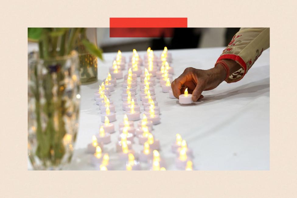 A woman lays a candle to join rows of others