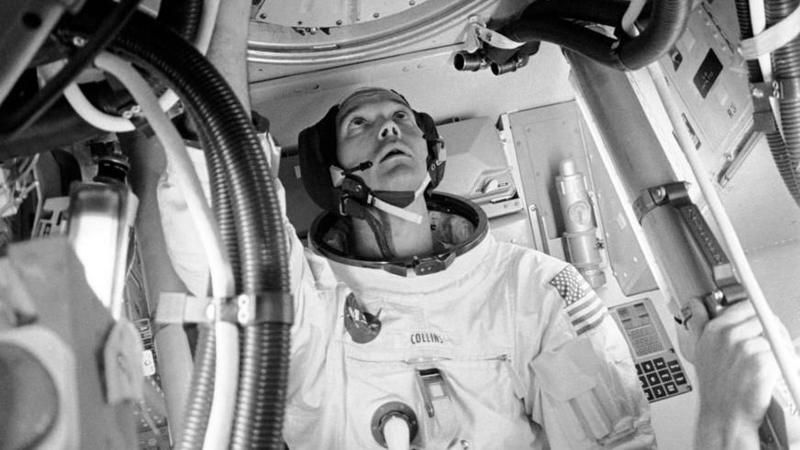 Astronaut Michael Collins looks up towards a portal inside the Apollo 11 module