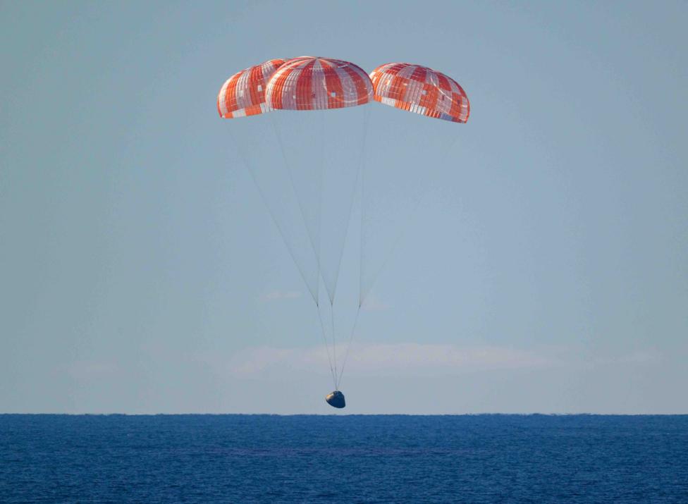 The landing craft with it's orange parachutes lands on a dark blue sea.