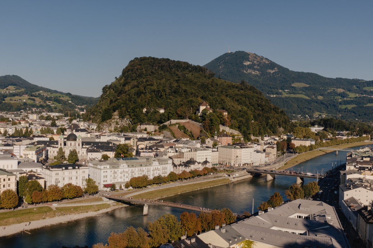 A view of a green hill seen across a river that is spanned by two bridges