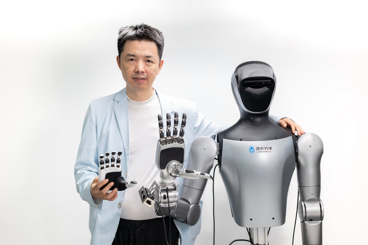 Alex Zhou, founder of tech startup Linkerbot, poses for a photo alongside a humanoid robot and a robotic dextrous hand at the company’s office in May in Beijing