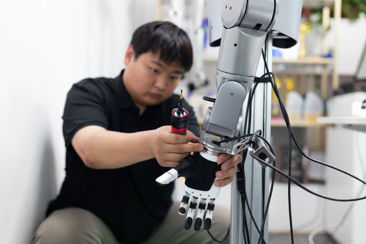 A technician calibrates a robotic dextrous hand mounted on a mechanical arm at Linkerbot