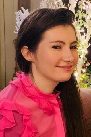 A woman in a pink top with brown hair 