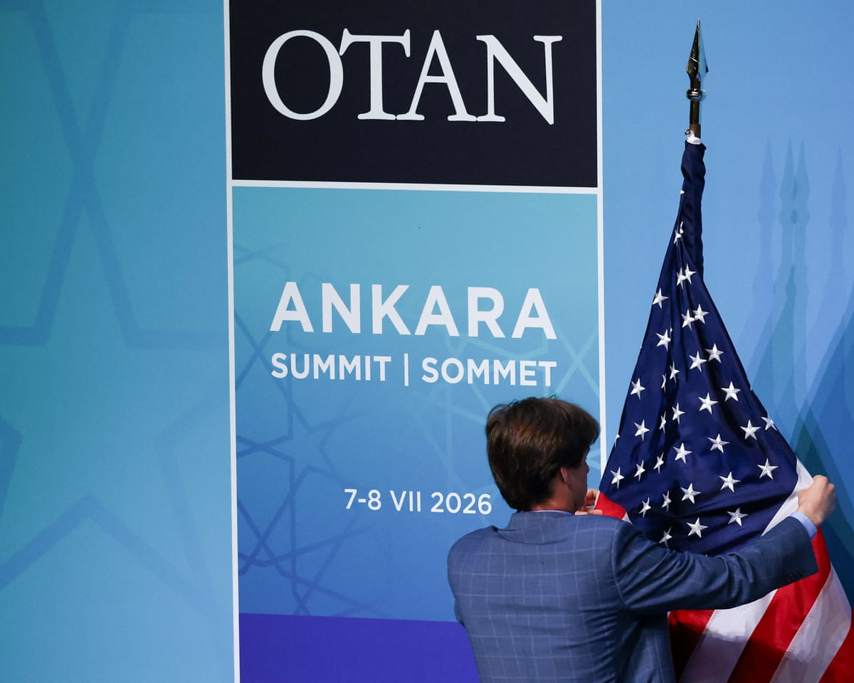 A worker adjusts a US flag before U.S. President Donald Trump speaks to the media on the day of a NATO leaders' summit in Ankara, Turkey.