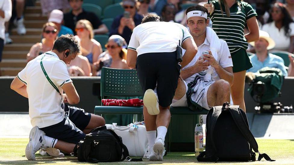 Taylor Fritz of United States receives medical treatment against Alexander Zverev of Germany