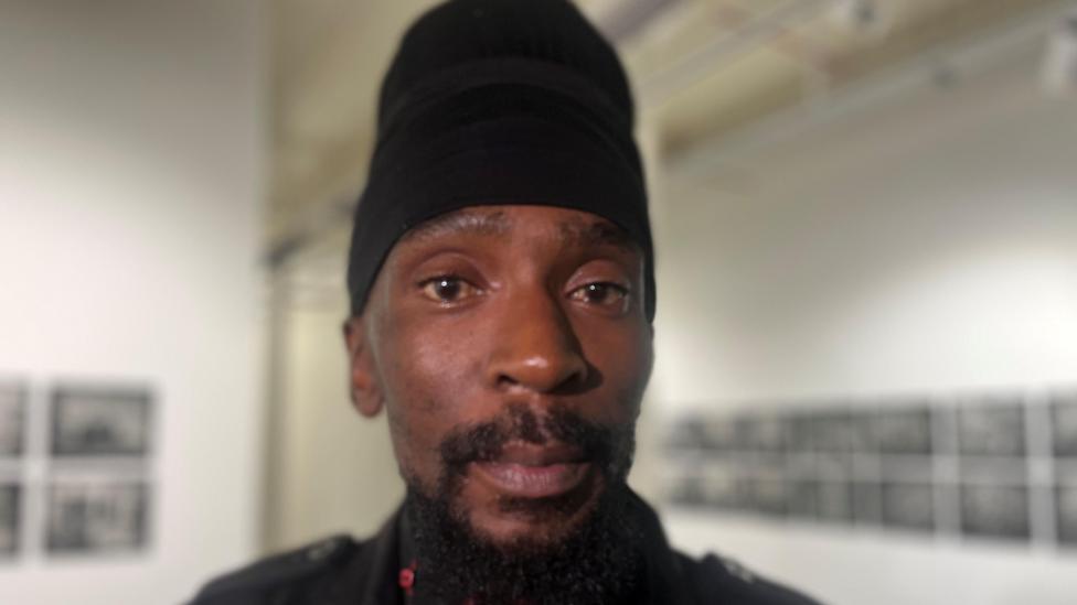 Takura Makoni is looking at the camera. He wears a black wrap on his hair.