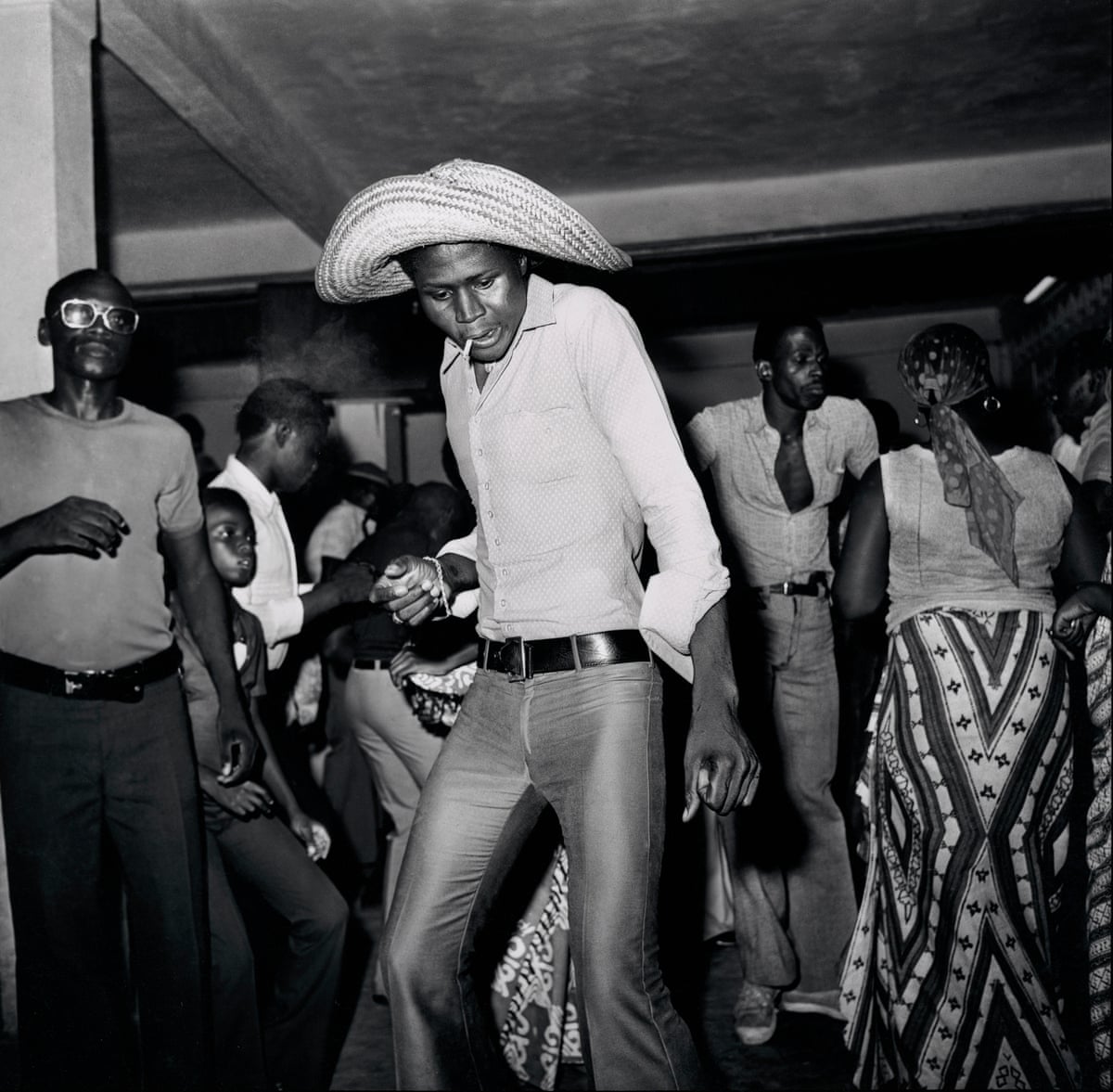 A man with a cool hat and a cigarette in his mouth dances in a nightclub in Ivory Coast
