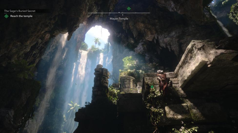 A screenshot. The main character is seen from a distance climbing rocks inside a cave. There is an opening near the top from which water is pouring, with light coming through too. It creates an effect of the scene being cinematically lit - a trick modern games often utilise.
