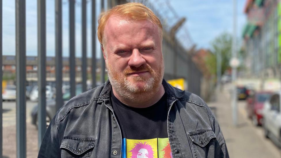 A man with red hair wearing a black coat and top