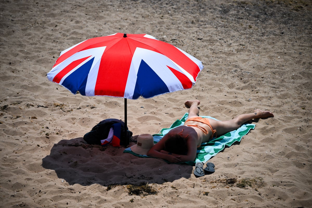 A woman sunbathing under a union flag parasol