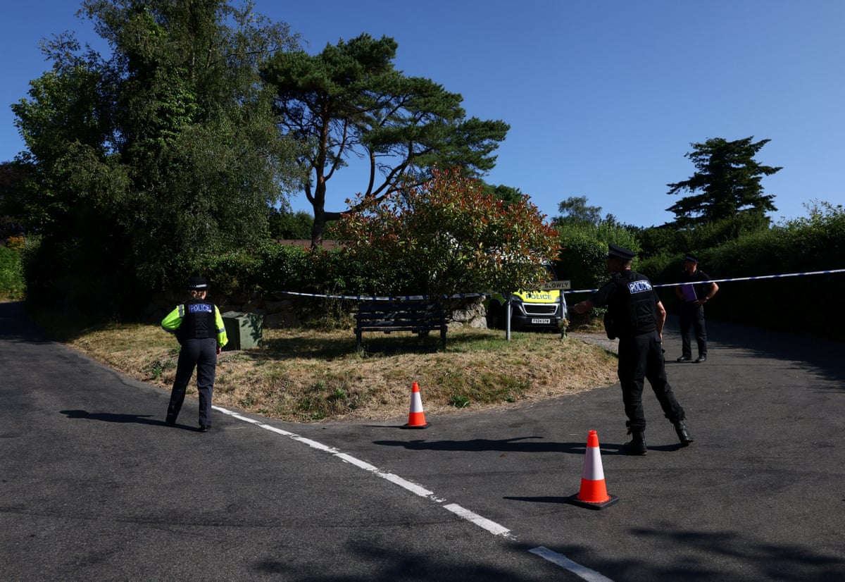 Police officers stand near a cordon tape as they investigate the home of Ann Widdecombe after she was found dead in Haytor.