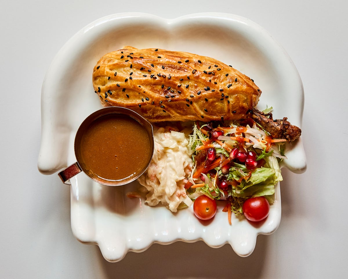 Dish containing pastry-wrapped chicken a side salad and bowl of gravy