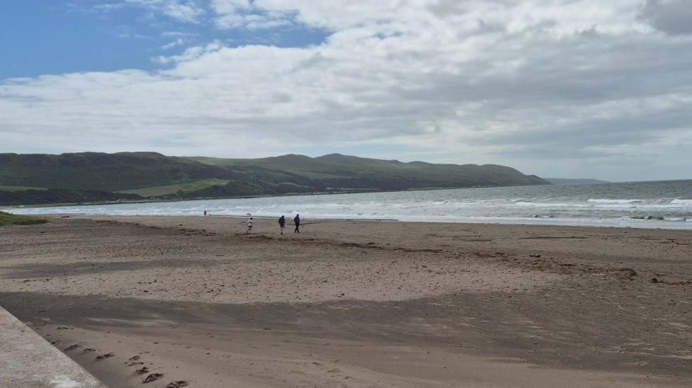 A beach, with only a few people on it.