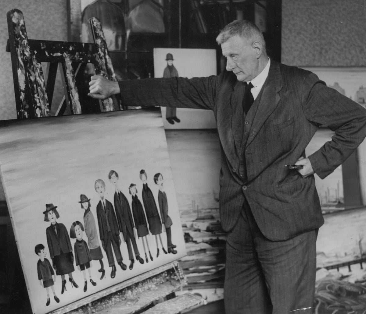 Lowry stands next to one of his paintings of some schoolchildren