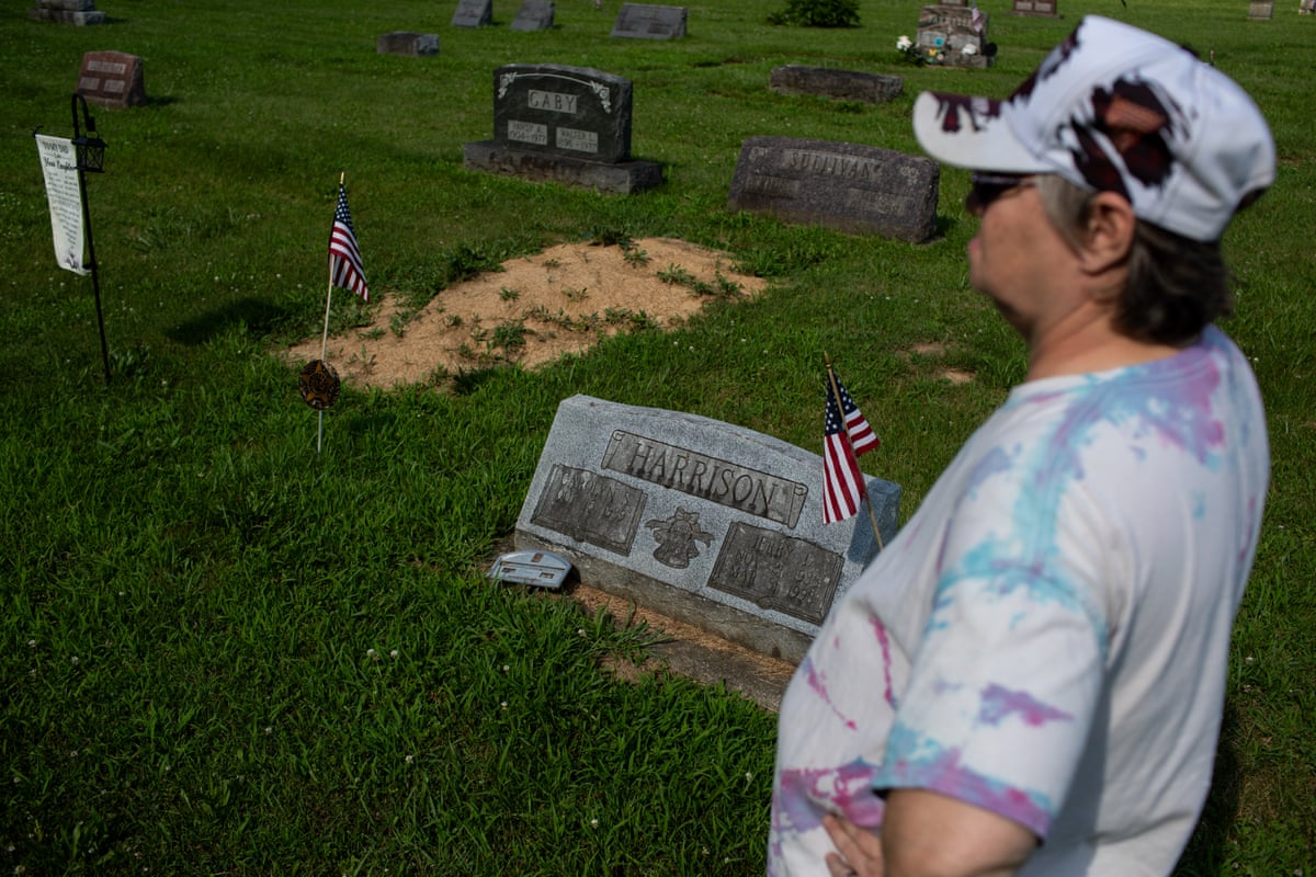 A woman at a burial plot with small US flags.