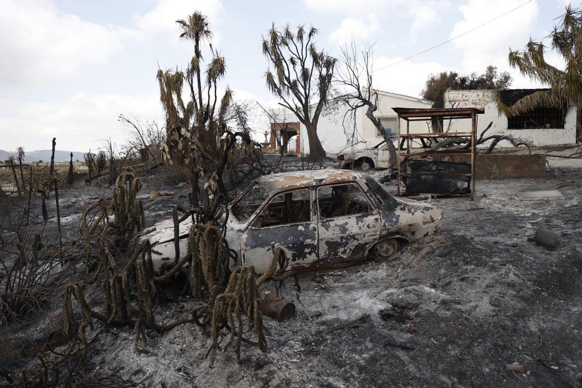 A burnt-out car in a scorched landscape