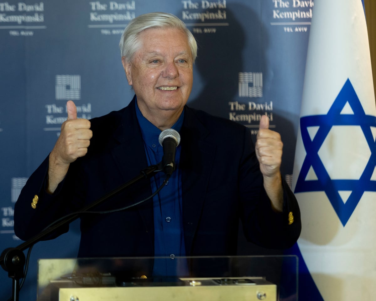 Lindsey Graham smiles and gives the thumbs up beside an Israeli flag