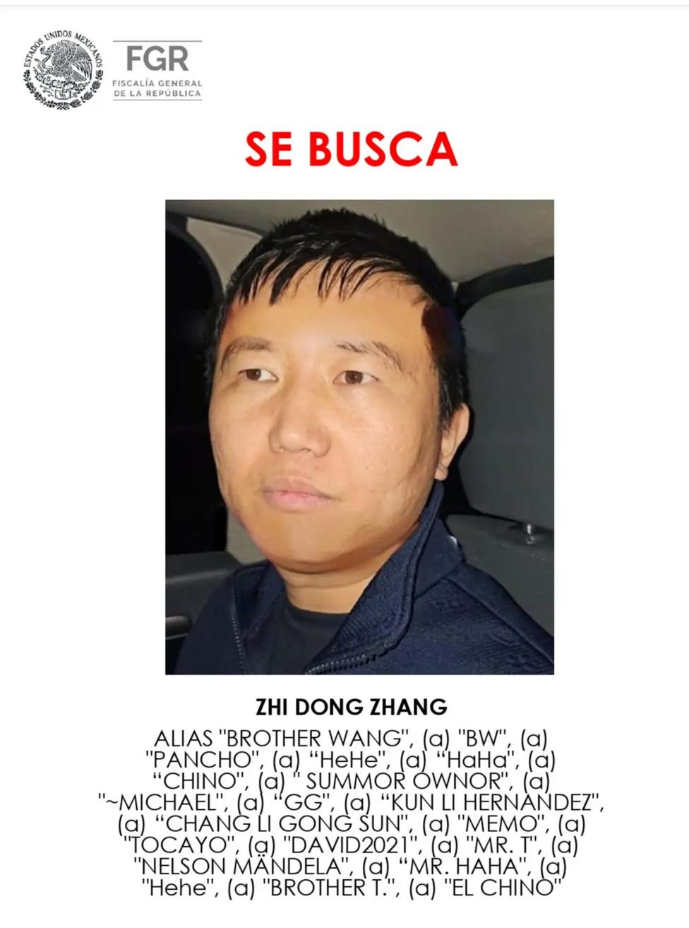 A poster showing Zhang's face - he has short dark hair. Above him are the words 'se busca' which translates as 'wanted'. Beneath him is a list of aliases including Pancho, China and Brother T.