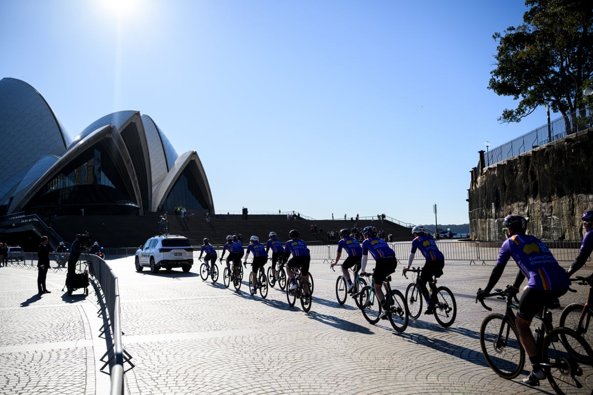 Members of the Tour de Cure peloton ride past the Sydney Opera House ahead of the service