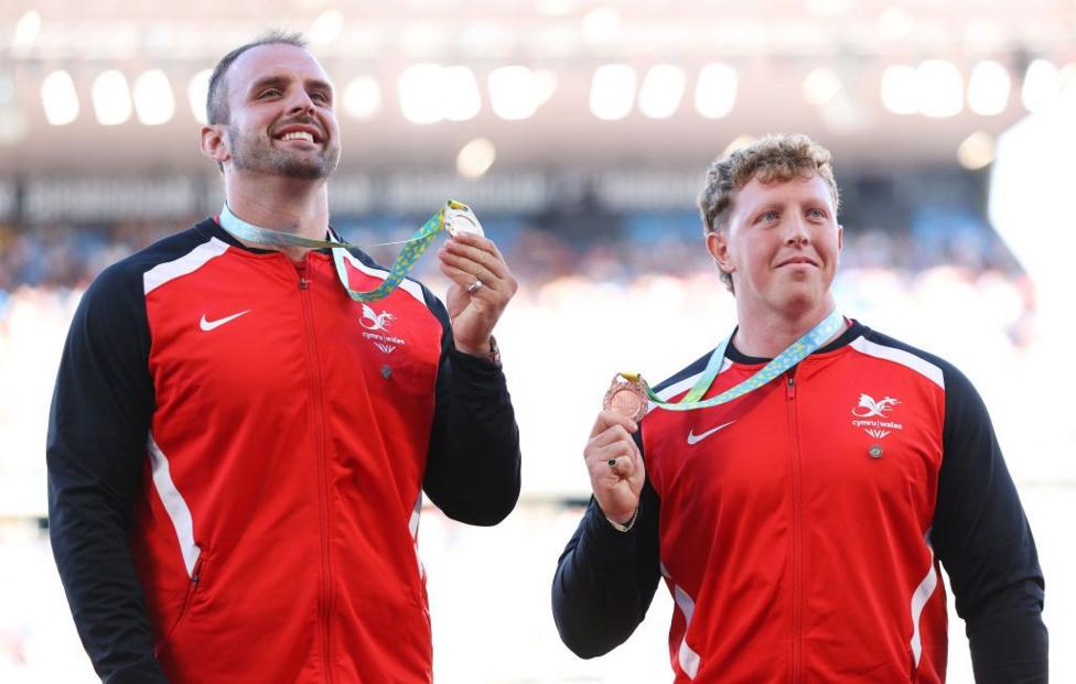 Aled Sion Davies (left) holds his gold medal aloft at the 2022 Commonwealth Games, standing alongside Wales' bronze medal winner Harrison Walsh.