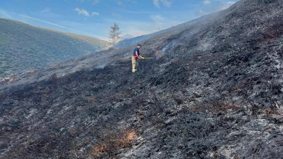 A firefighter damping down hot spots following a moorland wildfire on Tintwistle Moor, above Woodhead Road in Glossop, Derbyshire.
