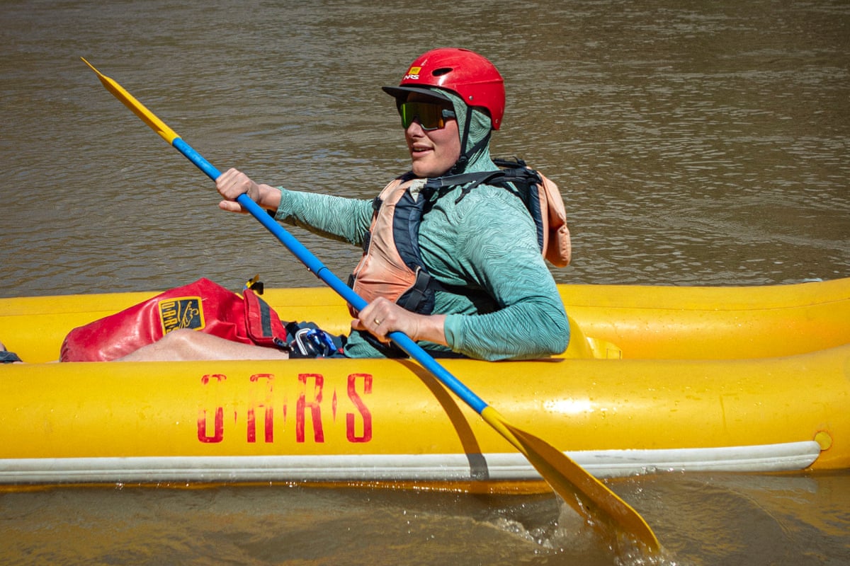 man in raft steers with paddles
