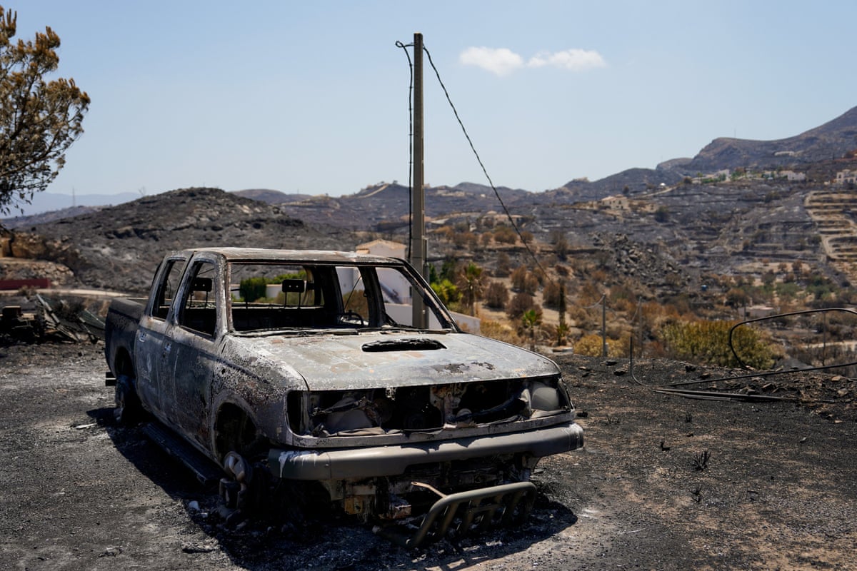 A burned-out car on a charred road in Bédar