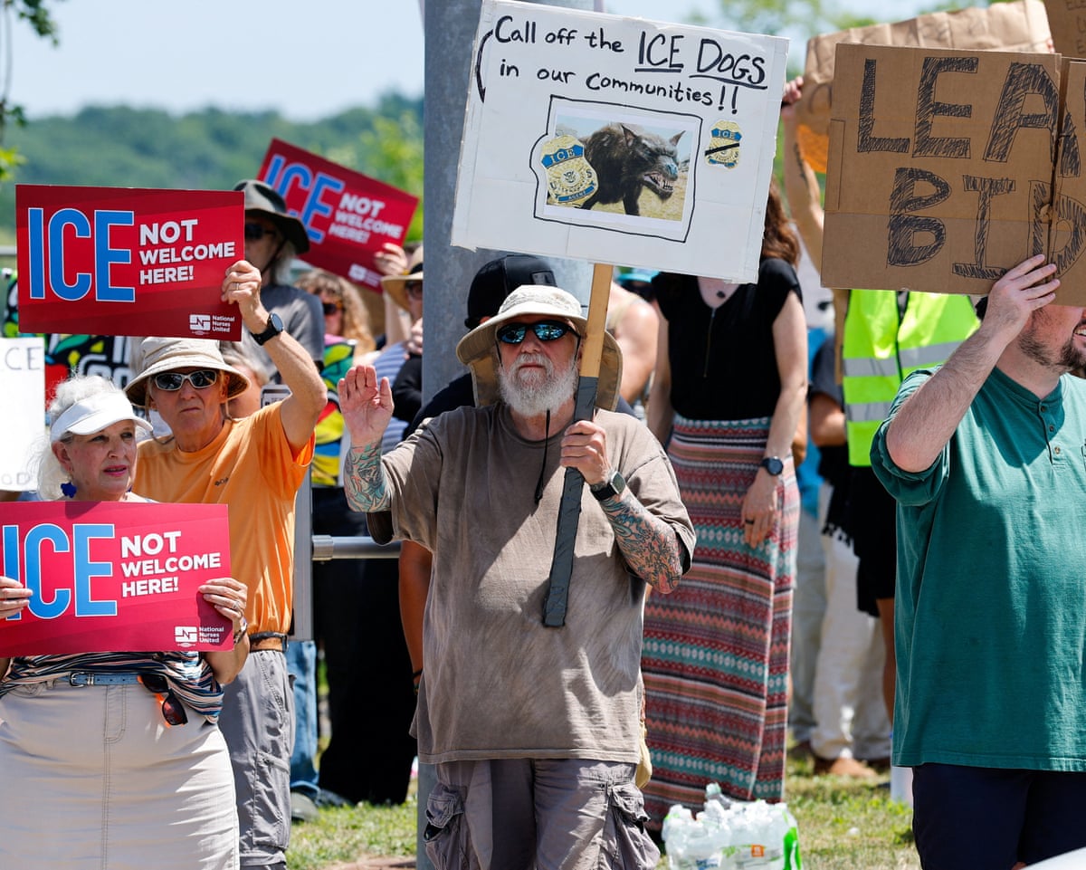 People hold placards as they take part in a protest at Mechanics Park after a shooting involving ICE in Biddeford, Maine.