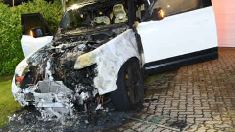 The white Land Rover is parked in a driveway. It has been badly damaged by fire