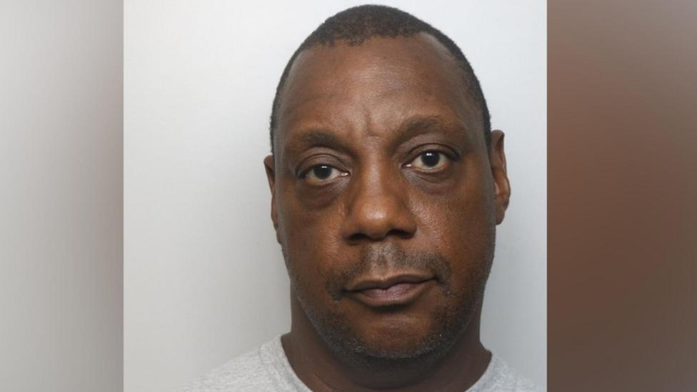 A mugshot of a man in a grey T-shirt looking at the camera.