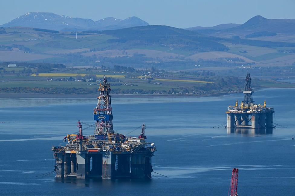 Two oil platforms on the Cromarty Firth - a clear blue stretch of water with hills and snow-capped mountains in the background