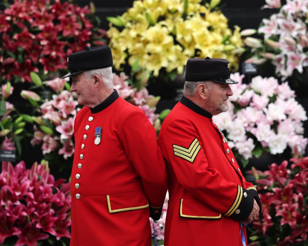 Chelsea pensioners wearing military dress standing in front of flower arrangements at the flower show