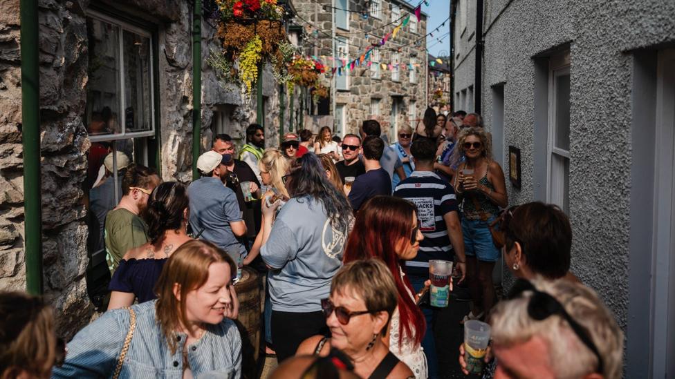 Criw yn cael llymaid ar y stryd fach rhwng tafarndai'r Torrent a'r Cross Keys Inn