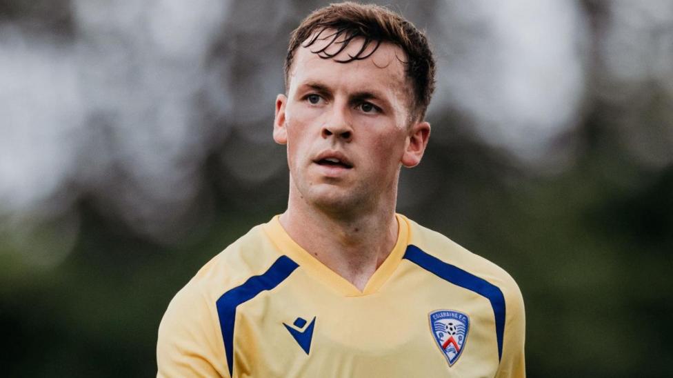 Ben Doherty has short brown hair and is wearing a blue and yellow Coleraine FC training shirt.