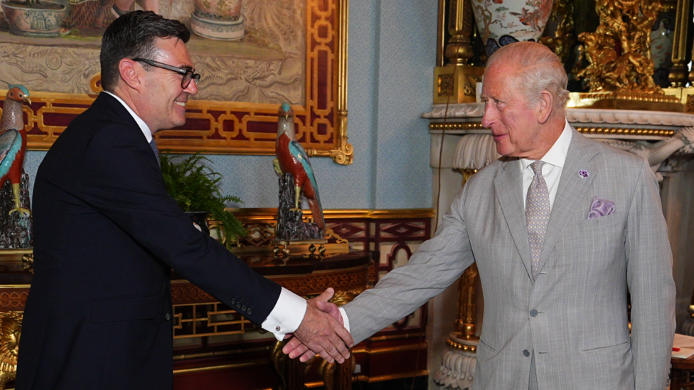 King Charles III shaking hands with Andy Burnham, during an audience at Buckingham Palace