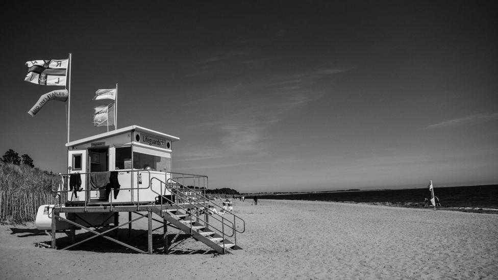 Black and white view of a beach safety hut on a beach.