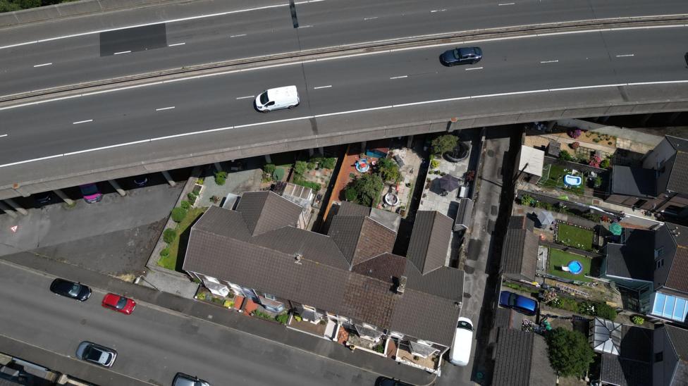 An overhead image from a drone showing how close to the M4 motorway the houses and gardens are. The image shows the motorway at the top of the image passing over the garden of a row of terraced houses