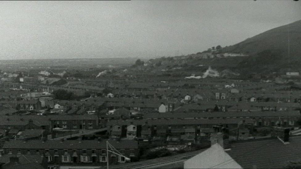 A black and white aerial image of the town of Port Talbot and its rows of terraced streets with a hill in the background