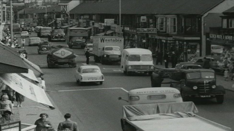 A black and white old image of the old A48 road that runs through Port Talbot from before the M4 motorway was built showing congestion as cars and lorries went slowly through the town