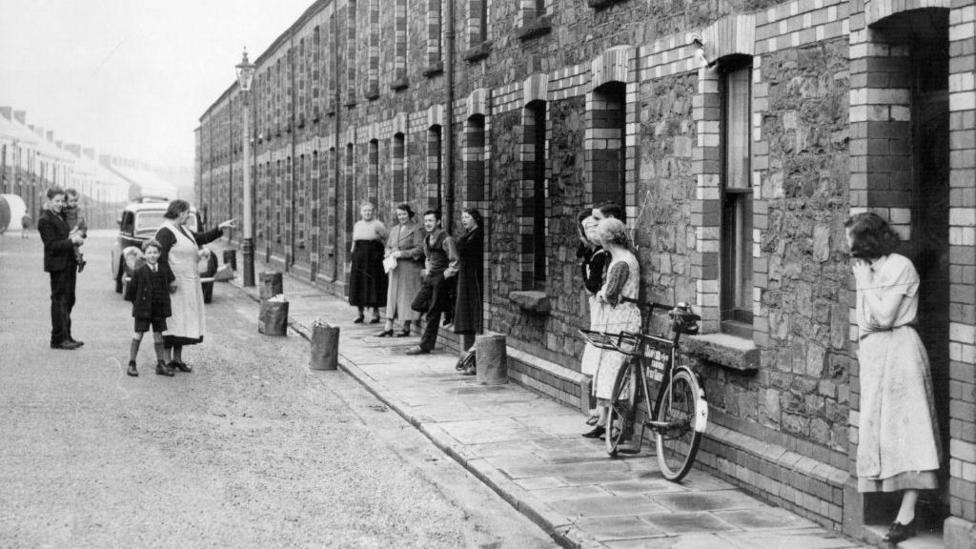 A black and white old image of some old residents of Llewellyn Street in Port Talbot outside their terraced houses