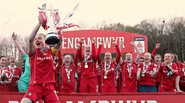 Wrexham captain Jodie Bartle lifts the Adran Premier Trophy in front of her team-mates