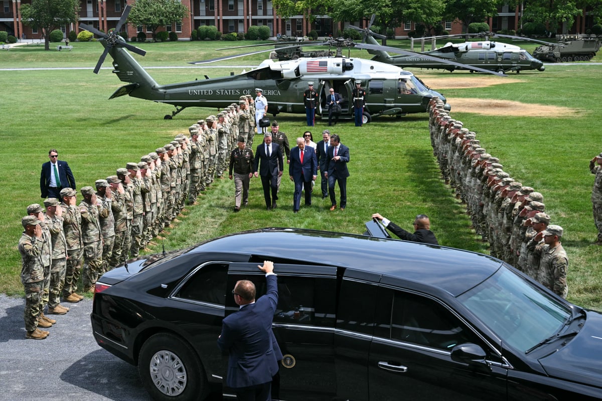 Donald Trump walks with officials as soldiers watch on
