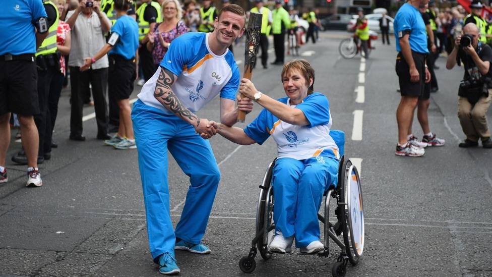 Ross Nixon and Dr Margo Whiteford, who is in a wheelchair, carry the Queens Baton Relay as it arrives in Glasgow on August 20, 2014.