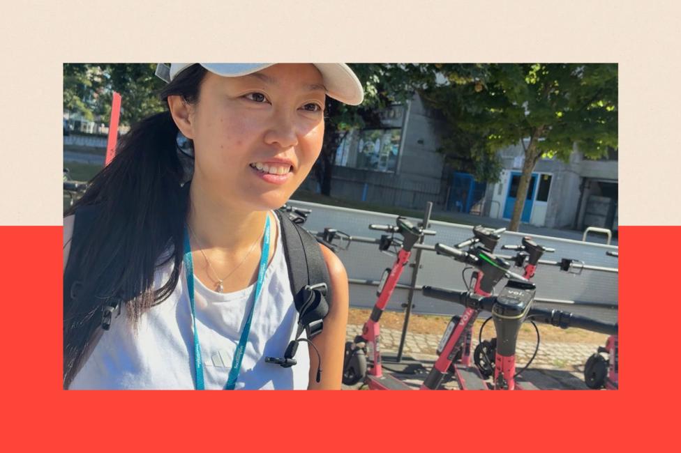 A picture shows Yan Zhang in the left of the frame. She is an Asian woman wearing a white baseball cap and a sleeveless light blue top. Behind on the right of the frame, a group of hire e-scooters are visible.