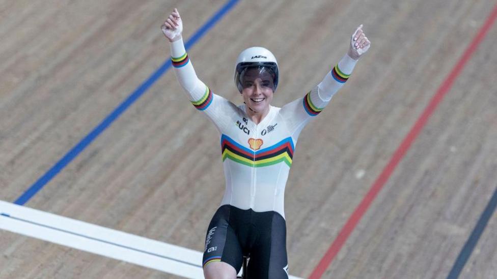 Emma Finucane wearing the world champion's rainbow jersey raises both arms in celebration as she crosses the line
