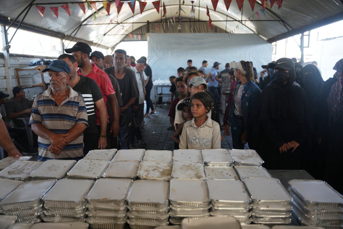 Displaced Palestinians wait to receive food at a community kitchen.