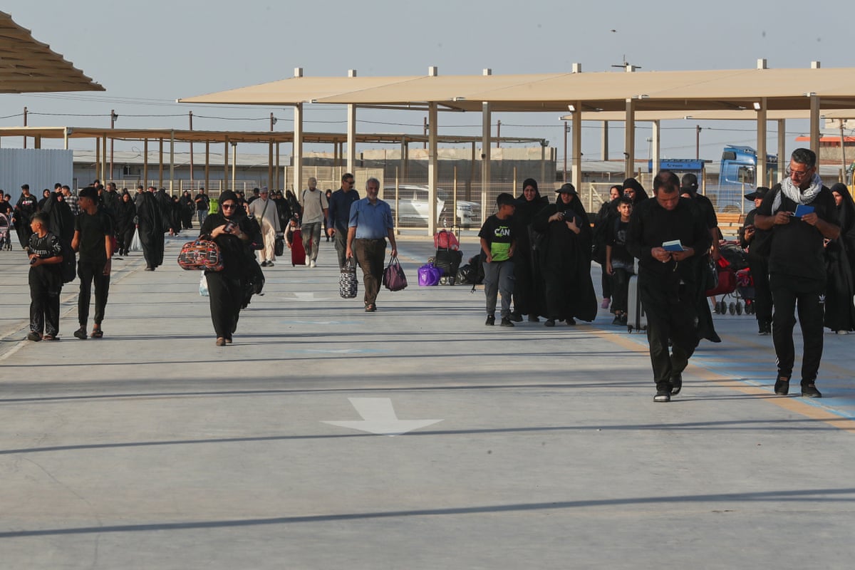 Dozens of people walking through a border crossing.