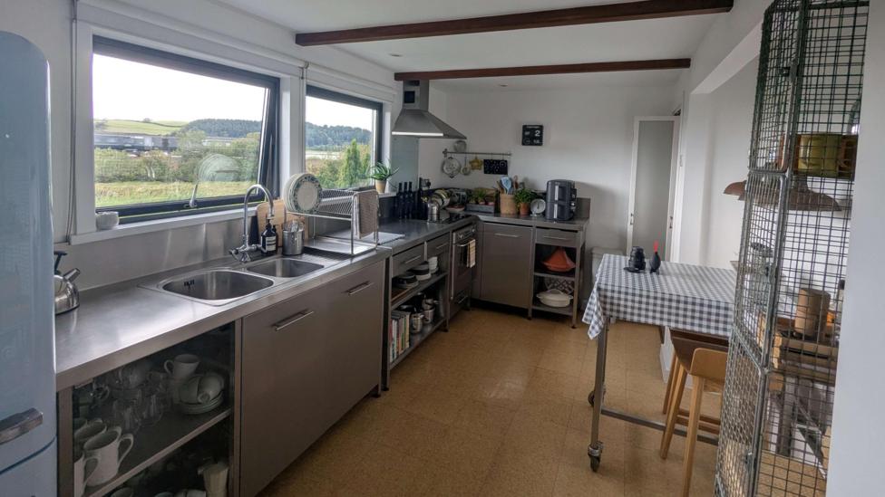 A kitchen with sliver hardware with everything neatly in its place. It has views of the countryside.